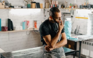 Business owner in workshop reflecting on future, representing business succession planning, ownership transfer, and preparing a company for continuity after death
