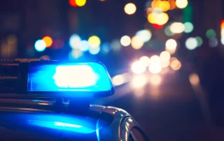 Police car with flashing lights at night, representing a DUI stop, criminal charges, and the impact on driving record and future driving privileges in Utah
