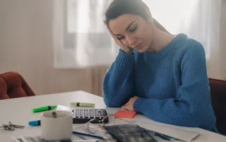 Woman reviewing bills and financial documents while comparing Chapter 7 and Chapter 13 bankruptcy options in Utah